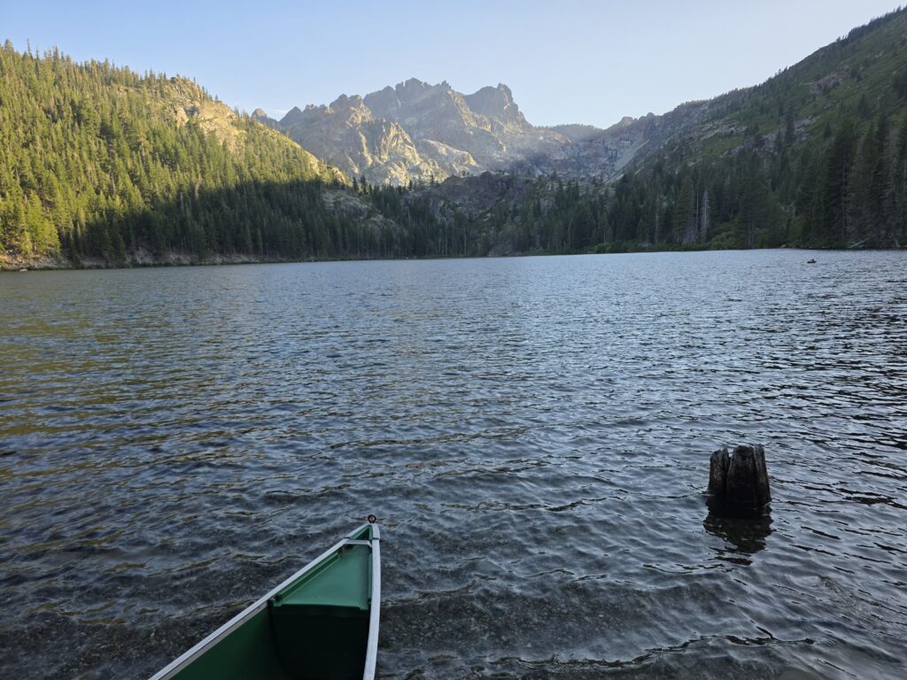 front end of canoe in lake with mountains in the distance